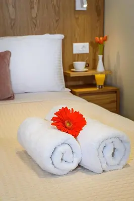 a white towel with a red flower on a bed at Nicolas Urban Luxury Living in Souda