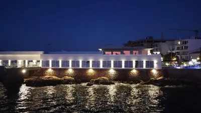 a building with lights on the water at night at Elia Sea Suites in Chania Town
