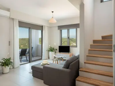a living room with a couch and stairs with a television at Panoramic view villa - Selita in Tavronitis