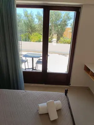 a bedroom with a bed and a window with a table at Talos in Sougia