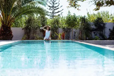 a woman sitting on the edge of a swimming pool at Nuera Villas in Chania Town