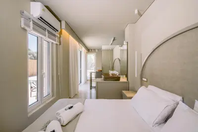 a bedroom with a white bed and a large window at Nidra Studio with private pool in Chania Town