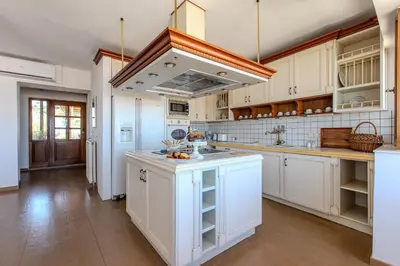 a kitchen with white cabinets and a large island at Platanias Memories Apartment in Plataniás