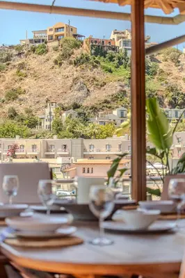 a table with wine glasses and a view of a mountain at Platanias Memories Apartment in Plataniás