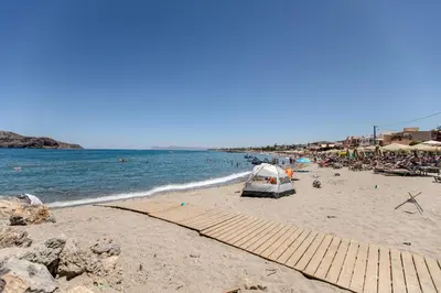 a sandy beach with chairs and umbrellas and the ocean at Platanias Memories Apartment in Plataniás