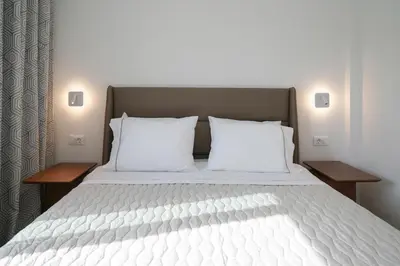 a bedroom with a large white bed with two pillows at Niki Luxury Suites Pool Resort 200m From Beach in Chorafakia