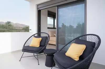 two wicker chairs with yellow pillows on a balcony at Niki Luxury Suites Pool Resort 200m From Beach in Chorafakia