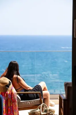 a woman sitting in a chair looking at the ocean at Kalyves Coastal Retreat in Chania Town