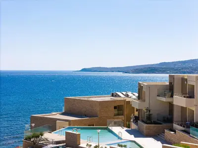 a building with a swimming pool next to the water at Kalyves Coastal Retreat in Chania Town