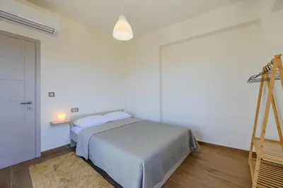 a white bedroom with a bed and a lamp at Serenity in Stérnai