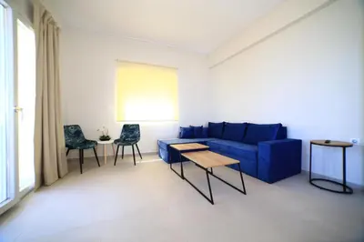 a living room with a blue couch and two chairs at GREEN n' BLUE apartments in Kalamaki Chanion