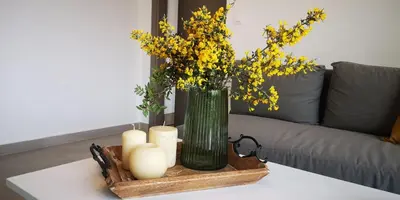 a vase with yellow flowers and candles on a table at Iris&Phaedra in Ayiá