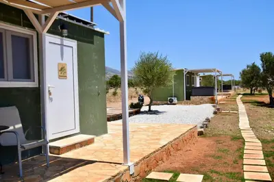 a green house with a white door and a patio at Agros simple living in Frangokastello