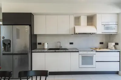 a kitchen with white cabinets and silver appliances at Nos Aqua Villas Chania in Pazinos