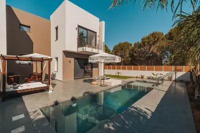 a villa with a swimming pool in front of a house at Nos Aqua Villas Chania in Pazinos