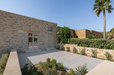 a stone house with a palm tree and a driveway at Villa Maistros in Kissamos