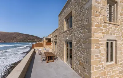 a building on the beach with a table and chairs at Villa Maistros in Kissamos