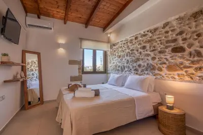 a bedroom with a bed and a stone wall at Superior Argilos Cottage Private Pool - 300m From the beach in Korfalónas