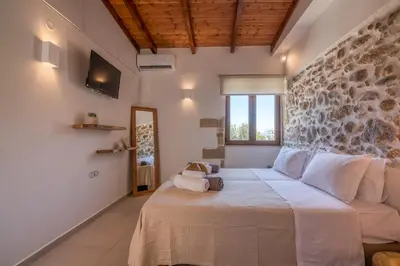 a bedroom with a bed and a stone wall at Superior Argilos Cottage Private Pool - 300m From the beach in Korfalónas
