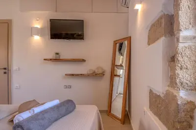 a living room with a couch and a tv on a wall at Superior Argilos Cottage Private Pool - 300m From the beach in Korfalónas