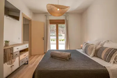 a bedroom with a large bed and a large window at Superior Argilos Cottage Private Pool - 300m From the beach in Korfalónas