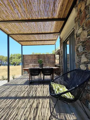 a patio with a table and chairs on a deck at Mekia's beach house in Livadia