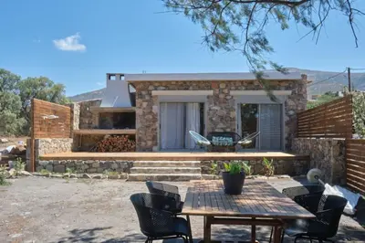 a patio with a table and chairs in front of a house at Mekia's beach house in Livadia