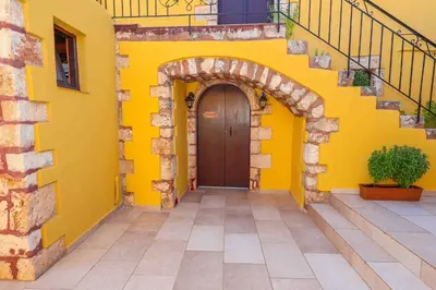 a yellow building with a wooden door and stairs at SternesVillage, Lower Ground Floor in Stérnai