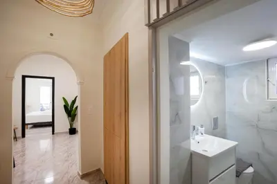 a white bathroom with a sink and a mirror at Sophia Apartment in Chania Town