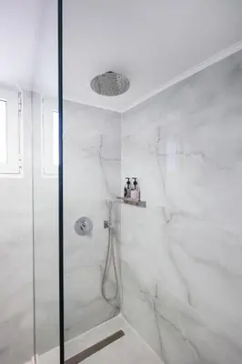 a bathroom with a shower with white marble walls at Sophia Apartment in Chania Town