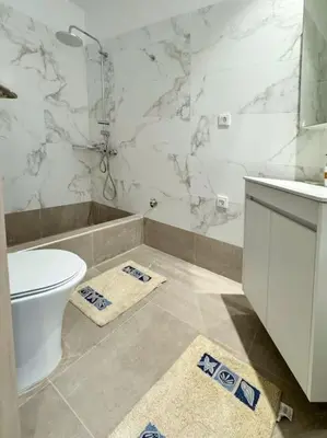 a white bathroom with a toilet and a shower at Christina & Suzan Apartment in Chania Town