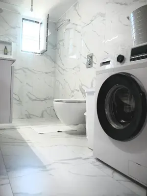 a white bathroom with a washing machine and a toilet at Kouklospito in Chania Town