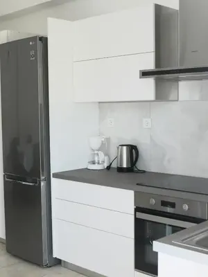 a kitchen with a stainless steel refrigerator and white cabinets at Kouklospito in Chania Town