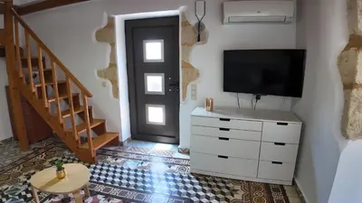 a living room with a tv and a dresser and a door at Stefanie's House in Chania Town
