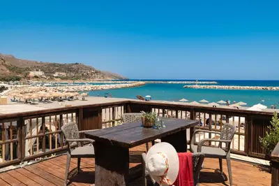 a table on a deck with a view of the beach at Ekati Seaside Living in Kolymvari