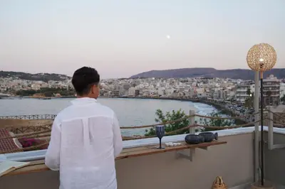 a man standing on a balcony looking at the water at Porta Harenae Residencia in Chania Town