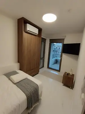 a bedroom with a bed and a cabinet and a window at The Athena Apartment, Chania Seaside in Chania Town