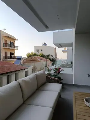 a living room with a white couch on a balcony at The Athena Apartment, Chania Seaside in Chania Town
