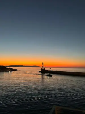 a lighthouse in the middle of the water at sunset at The Athena Apartment, Chania Seaside in Chania Town