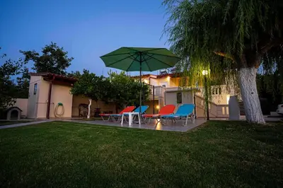 a patio with chairs and a table with an umbrella at Villa Marianna Lygides in Ayiá