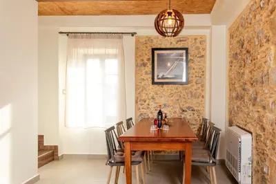 a dining room with a wooden table and chairs at Villa Elpida in Myloniana in Milonianá