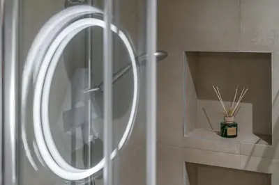 a bathroom with a mirror and a vase of sticks at Leo Apartment 2 bdr apt overlooking the harbor in Chania Town