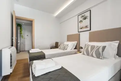 two beds in a room with white walls and wooden floors at Comfy Apt terrace and parking 800m to old town and beach in Chania Town
