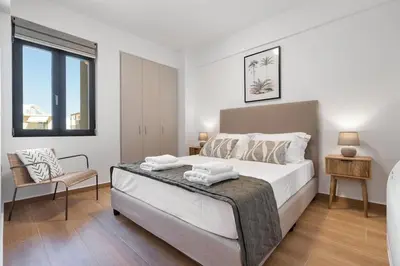 a bedroom with a large white bed and a chair at Comfy Apt terrace and parking 800m to old town and beach in Chania Town