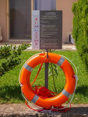 an orange life raft sitting on the grass next to a sign at Cisterna Apartment - Shared Pool in Stérnai