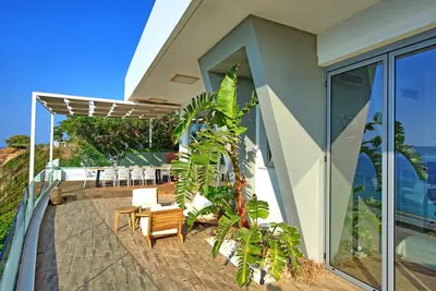 a patio with chairs and tables on a house at Villa Sapphire by PosarelliVillas in Almirida
