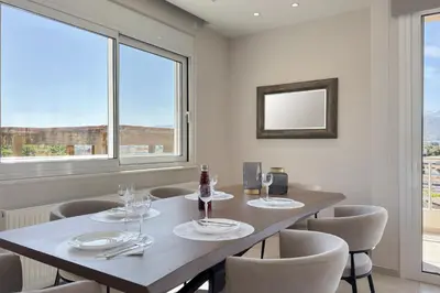 a dining room with a table and chairs and windows at Ardian's home in Chania Town
