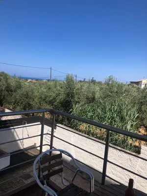 a chair sitting on a deck next to some bushes at Helen in Pírgos Psilonérou