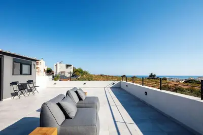 a balcony with a couch and a view of the ocean at Ikon Living Chania in Chania Town