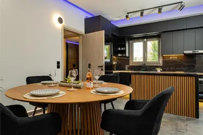 a kitchen and dining room with a wooden table and chairs at Noir Residence - Chic 2Br House Near Maleme Beach in Maleme